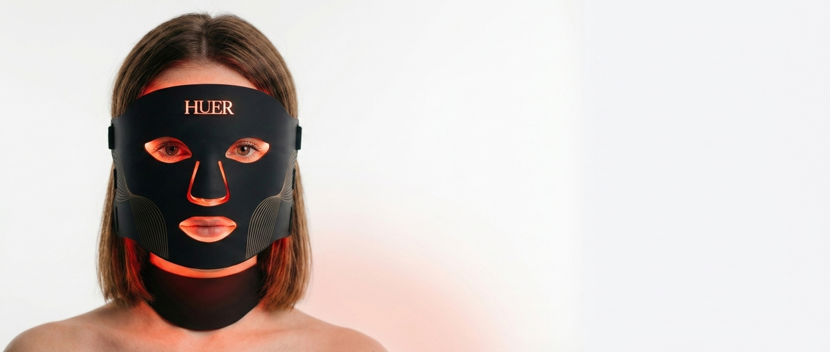 Woman wearing the HUER LED face and neck mask in red light mode